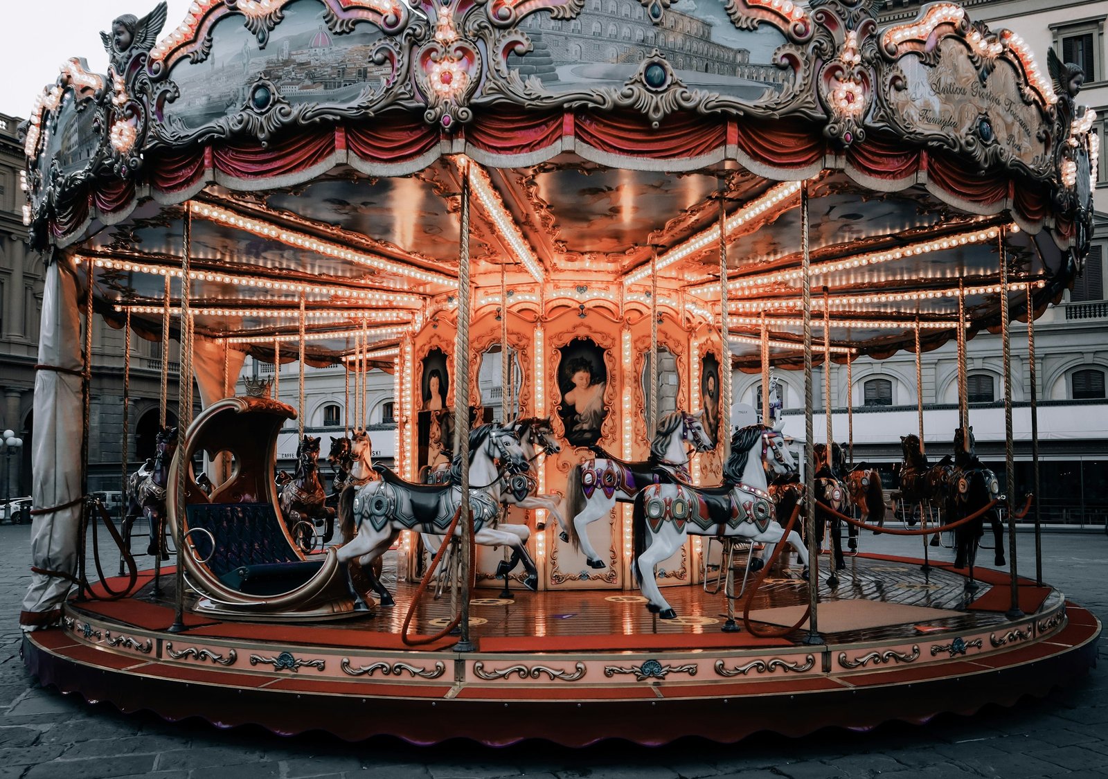 Un carrousel ancien aux chevaux blancs et aux drapés rouges, à la tombée du jour